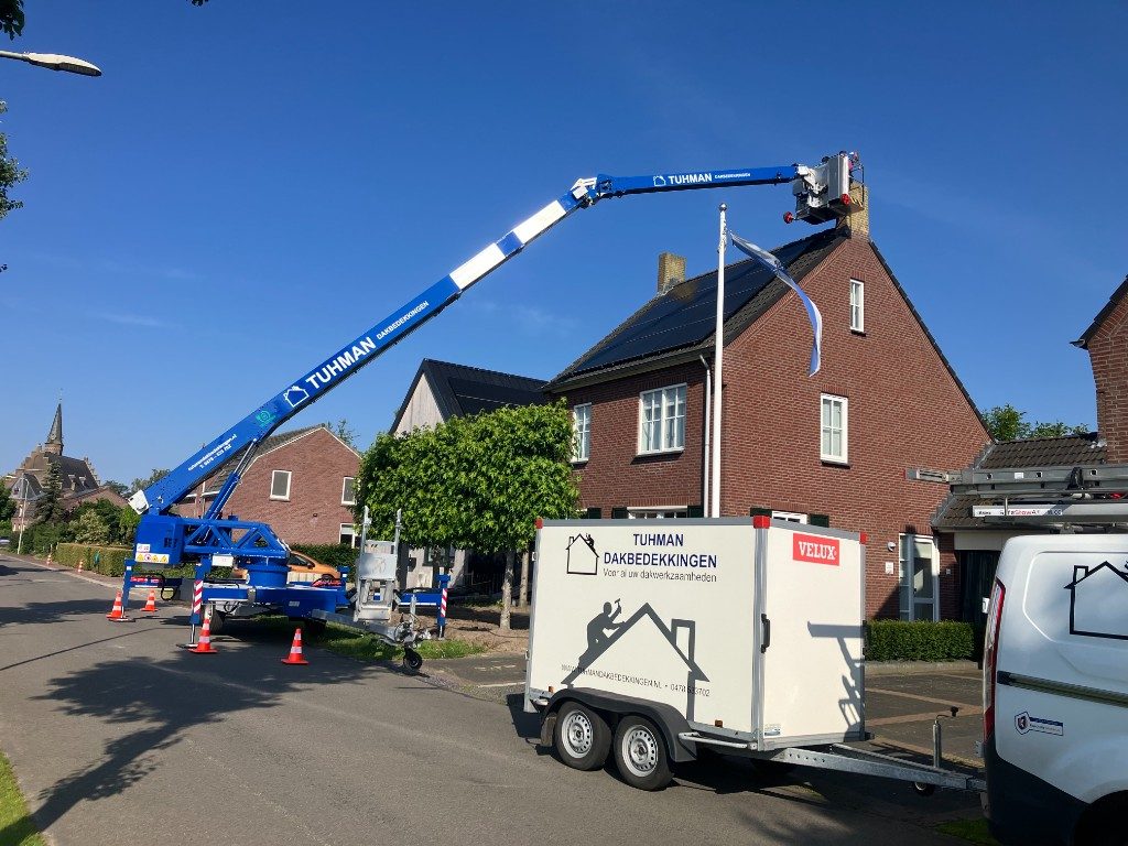 Tuhman met hoogwerker en aanhanger bij de schoorsteen van een woning